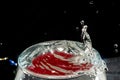 Transparent glass bowl, filled with water, with red reflection and splashing drops. Splash Effect Royalty Free Stock Photo