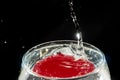 Transparent glass bowl, filled with water, with red reflection and splashing drops. Splash Effect Royalty Free Stock Photo