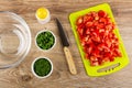 Transparent bowl, salt, bowls with chopped scallion and dill, knife, pieces of tomatoes on cutting board on table. Top view Royalty Free Stock Photo