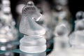 Transparent glass chess on dark background, selective focus on horse piece, close-up Royalty Free Stock Photo