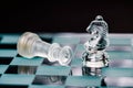 Transparent glass chess on dark background, selective focus on horse piece, close-up Royalty Free Stock Photo