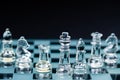 Transparent glass chess pieces arranged in a row reflecting in glass chessboard. Isolated on black Royalty Free Stock Photo