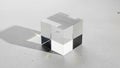 A transparent glass cube sits on a light gray textured surface Royalty Free Stock Photo