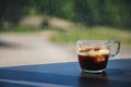 Transparent glass cup of ice coffee placed on a dark wooden lami