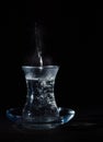 Transparent glass cup with swell the boiling water into it. The vapor from the top. Black background. Royalty Free Stock Photo