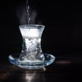 Transparent glass cup with swell the boiling water into it. The vapor from the top. Black background. Royalty Free Stock Photo