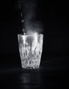 Transparent glass cup with swell the boiling water into it. The vapor from the top. Black background. Royalty Free Stock Photo