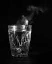 Transparent glass cup with swell the boiling water into it. The vapor from the top. Black background. Royalty Free Stock Photo