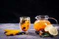 Transparent glass cup and teapot with exotic fruit tea, on a black and gray background