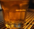 A transparent glass filled with water.The cups are placed on the counter of the coffee machine.The transparent glass is an accesso