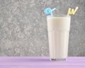 Transparent glass with fresh organic milk,cocktail tubules on a pastel color wooden table on the background of a concrete wall.