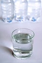 A transparent glass full of water. near a bottle of mineral water.