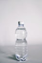 A transparent glass full of water. near a bottle of mineral water.