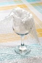 Transparent glass goblet half packaged with cellophane bubble wrap on a white blue checkered tablecloth. Material for packing