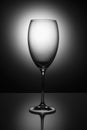 Transparent  glass goblet without wine on a thin leg stands on a mirror surface Royalty Free Stock Photo