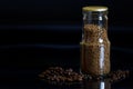 Transparent glass jar sealed with foil next to roasted coffee beans on a dark gradient background. Copy space. Photo