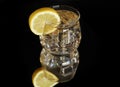 Transparent glass with lemon tea, ice and lemon slice reflected on black background Royalty Free Stock Photo
