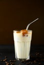 Transparent glass with milk and ice cubes made from coffee. Iced coffee with a metal tube on a dark brown background. Royalty Free Stock Photo