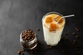 Transparent glass with milk and ice cubes made from coffee. Iced coffee with a metal tube and grains in a jar on a dark Royalty Free Stock Photo