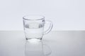 Transparent glass mug with water on light reflective surface Royalty Free Stock Photo