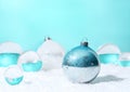 Transparent glass orbs and Christmas balls with white snow on cyan background.