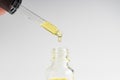 Transparent glass pipette with facial serum, bubbles on white background. Medical research concept. Dropper with drop of essential