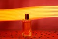 Transparent glass rectangular bottle of perfume on golden neon background. Copy space
