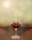 Transparent glass with red wine, light lens flare background, wood texture table, close up Royalty Free Stock Photo