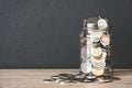 transparent glass savings jar filled with coins on wooden table with black color wall background, copy space Royalty Free Stock Photo