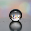A transparent glass sphere rests on a reflective surface, capturing vibrant multi-colored Royalty Free Stock Photo
