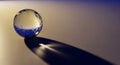 A transparent glass sphere rests on a smooth surface, casting a long shadow. The Royalty Free Stock Photo
