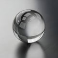 A transparent glass sphere sits on a reflective, brushed metal surface. The sphere Royalty Free Stock Photo