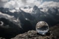 Transparent glass sphere and snow-capped peaks in the background Royalty Free Stock Photo