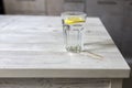 Transparent glass tables with a slice of lemon is on a wooden table in beige kitchen interior. Empty space