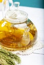 Transparent glass teapot made of borosilicate glass with herbal tea and lemon on a blue background