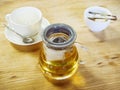 A transparent glass teapot with tea next to a vase with sugar and a clean cup stand on a wooden surface. Tea party