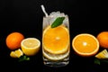Transparent glass with water with bubbles, round slice of orange inside, ice and mint leaf, half juicy and ripe orange and lemon Royalty Free Stock Photo