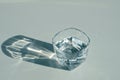 Transparent glass of water on a white background with a sunbeam, close up