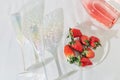 Transparent Glasses, bottle with rose sparkling wine and red berries strawberry on white table with sunlight Royalty Free Stock Photo