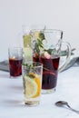 transparent glasses with liquid with glass decanters and a spoon lying on the table. juice and compote in a glass with lemon