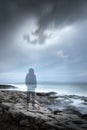 Transparent gloomy hooded man silhouette in a seascape
