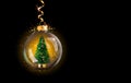 Transparent golden ball with Christmas tree inside on black background