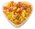 Transparent heart shape vase (bowl) filled with colored (red, yellow an orange) heart shape pasta, white background Royalty Free Stock Photo