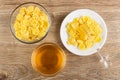 Honey dipper on corn flakes with honey in saucer, bowl with cornflakes, bowl with honey on table. Top view