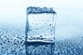 Transparent ice cube with reflection on blue glass with water drops Royalty Free Stock Photo