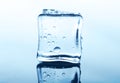 Transparent ice cube with reflection on blue glass with water drops Royalty Free Stock Photo