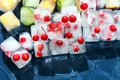 Transparent ice cubes with berries and fruit. Frozen edible ice close-up