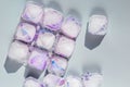 Transparent ice cubes with purple flower petals. Frozen edible ice close-up