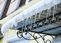 Transparent icicles from the frozen melting snow will rise on the roof of the balcony. Royalty Free Stock Photo