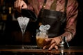 transparent martini glass full of ice and glass of shaker with cocktail in which pouring ice cubes are on bar counter Royalty Free Stock Photo